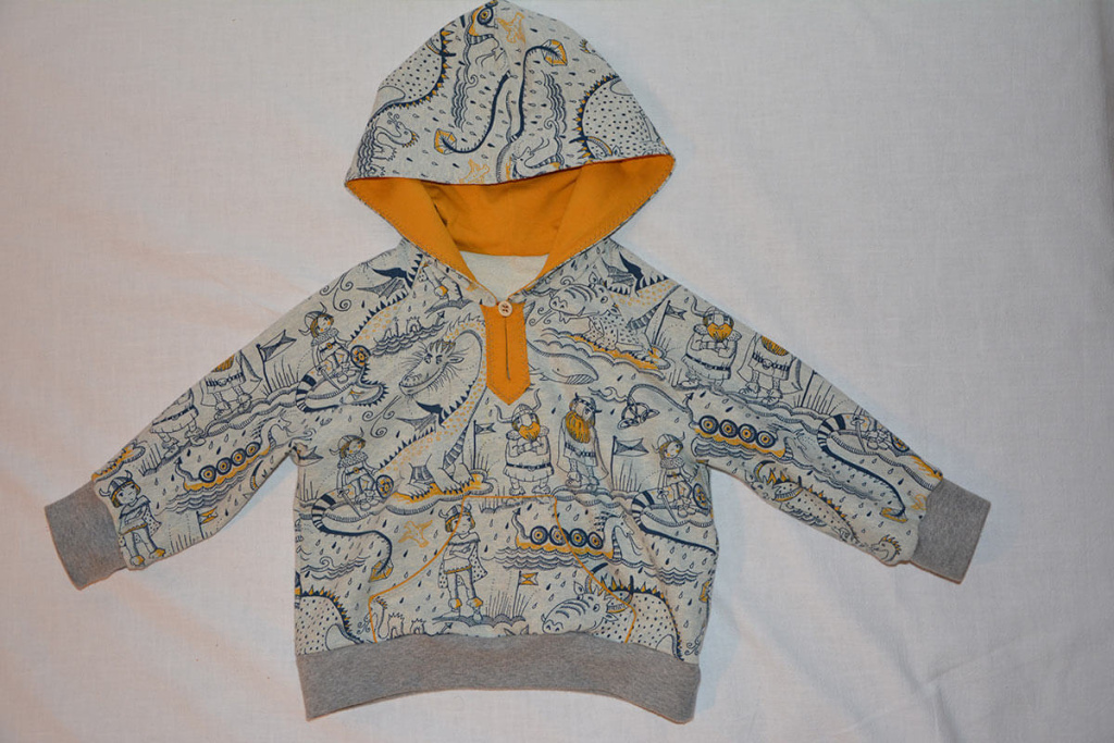 Bunte Kinderhoodie mit märchenhaften Motiven und orangefarbener Kapuze.