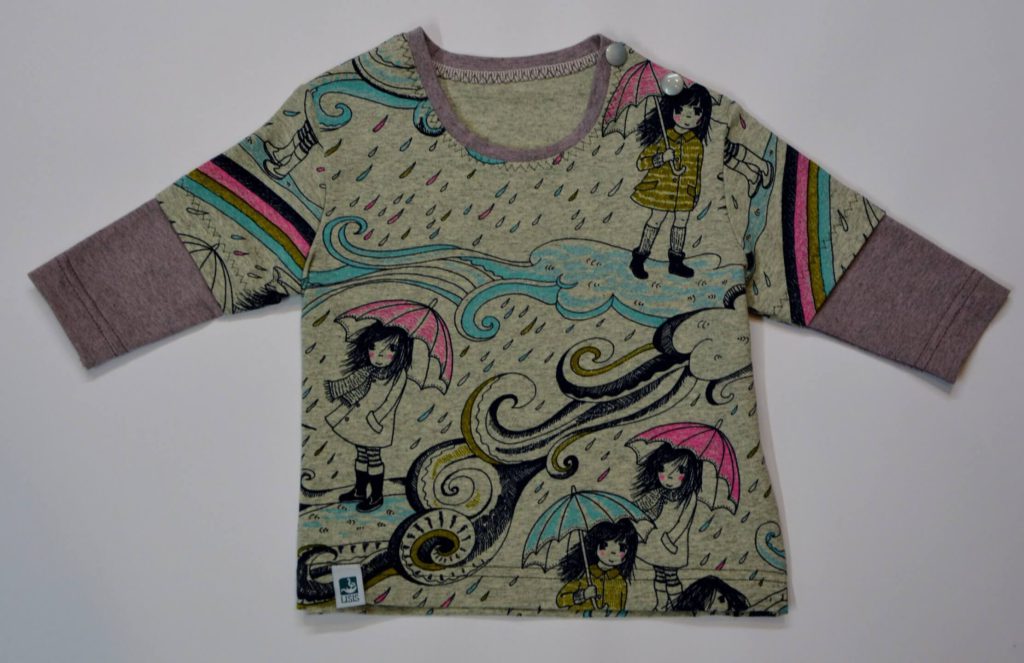 Bunt bedrucktes Kinderoberteil mit Regenschirm-Motiv und farbigen Ärmeln.