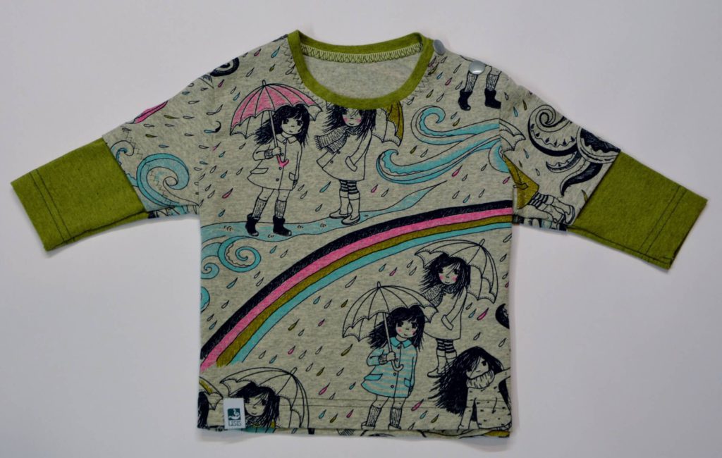 Bunt bedrucktes Kinderoberteil mit Regenmädchen und Regenbogenmotiven.